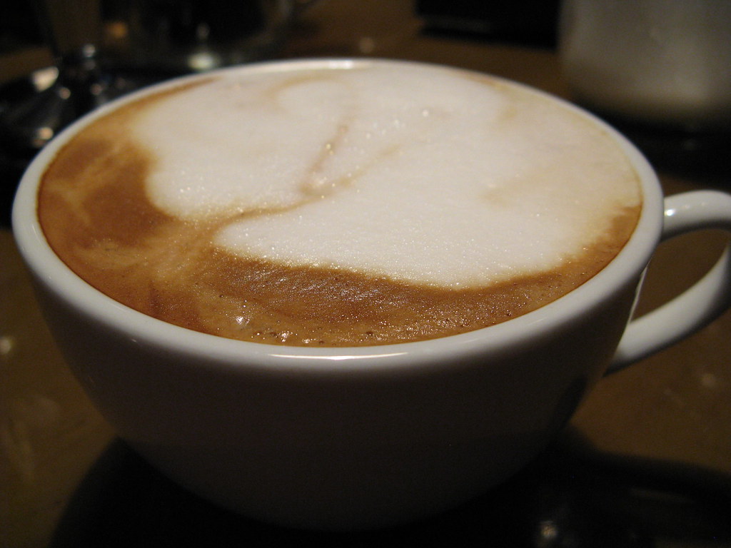 Latte con arte en la espuma, en vaso de vidrio
